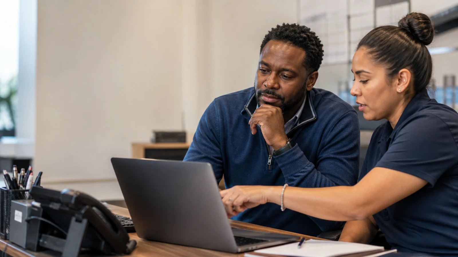 Small business manager and employee reviewing an AI-assisted customer complaint response before sending it